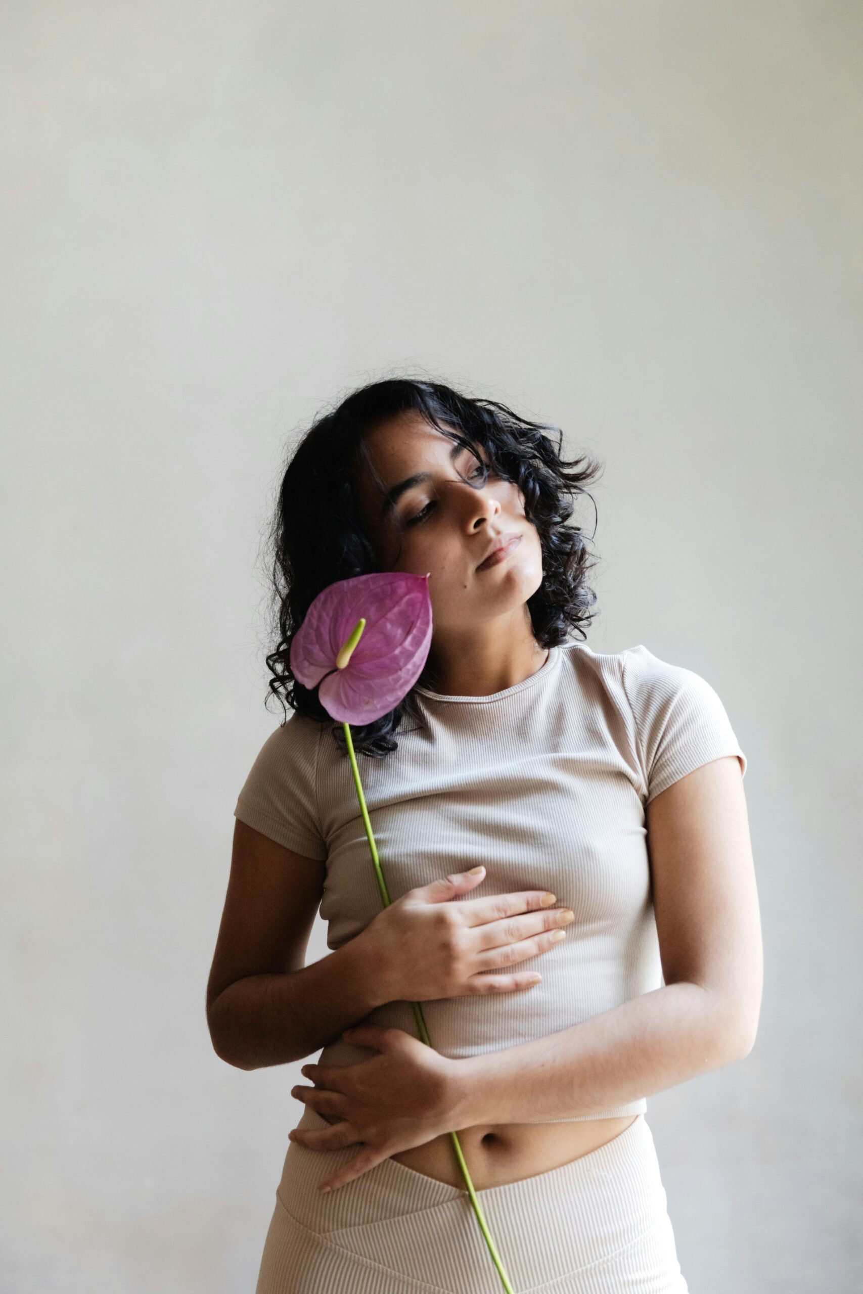 a woman holding an orchid and cradling her stomach